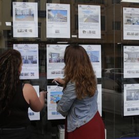 Dos jóvenes comparan ofertas inmobiliarias. Hipotecas.