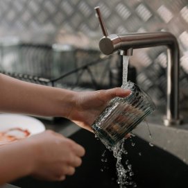 Una persona limpia un vaso el grifo. Foto: Pexels.