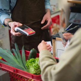 Trabajador de comercio cobrando a unos clientes.
