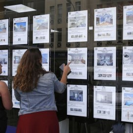 Dos jóvenes comparan opciones de vivienda en una agencia inmobiliaria