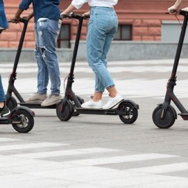 Varios jóvenes se desplazan en patinete eléctrico. Transporte.