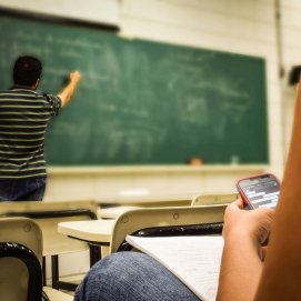 Docente dando clase mientras una estudiante usa el móvil. Foto: Pexels