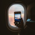Una mujer fotografía el cielo con su móvil desde un avión. Vuelos.