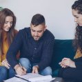 Una pareja firma un contrato de arras frente a una agente inmobiliaria. Hipotecas.