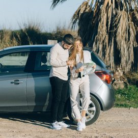 Una pareja comprueba su destino vacacional con su coche de alquiler. Sanción.